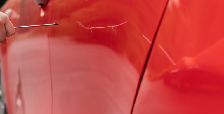 Rotes Auto mit Kratzer zu sehen, Kinderhand mit einem Schraubenzieher. | © Foto: Yakovlev Mikhail/Shutterstock.com 