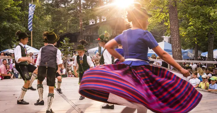 Tanzen Frau in Tracht auf Tanzparkett im Wald, um sie herum Jungs in Tracht tanzend.  | © Foto: Waldfest Kreuth, © Der Tegernsee, Dietmar 