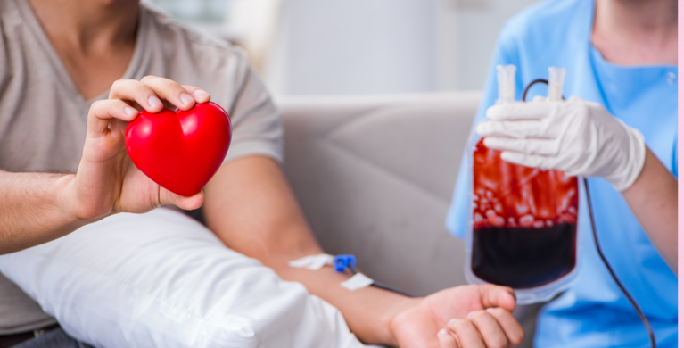 Auf dem Foto ist eine rote Blutkonserve und ein rotes Herz zu sehen, das von Händen gehalten wird. 