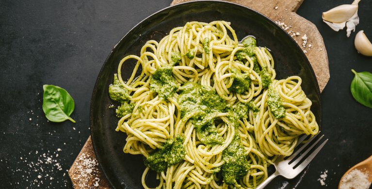 Ein Teller mit Spaghetti grünem Pesto. 